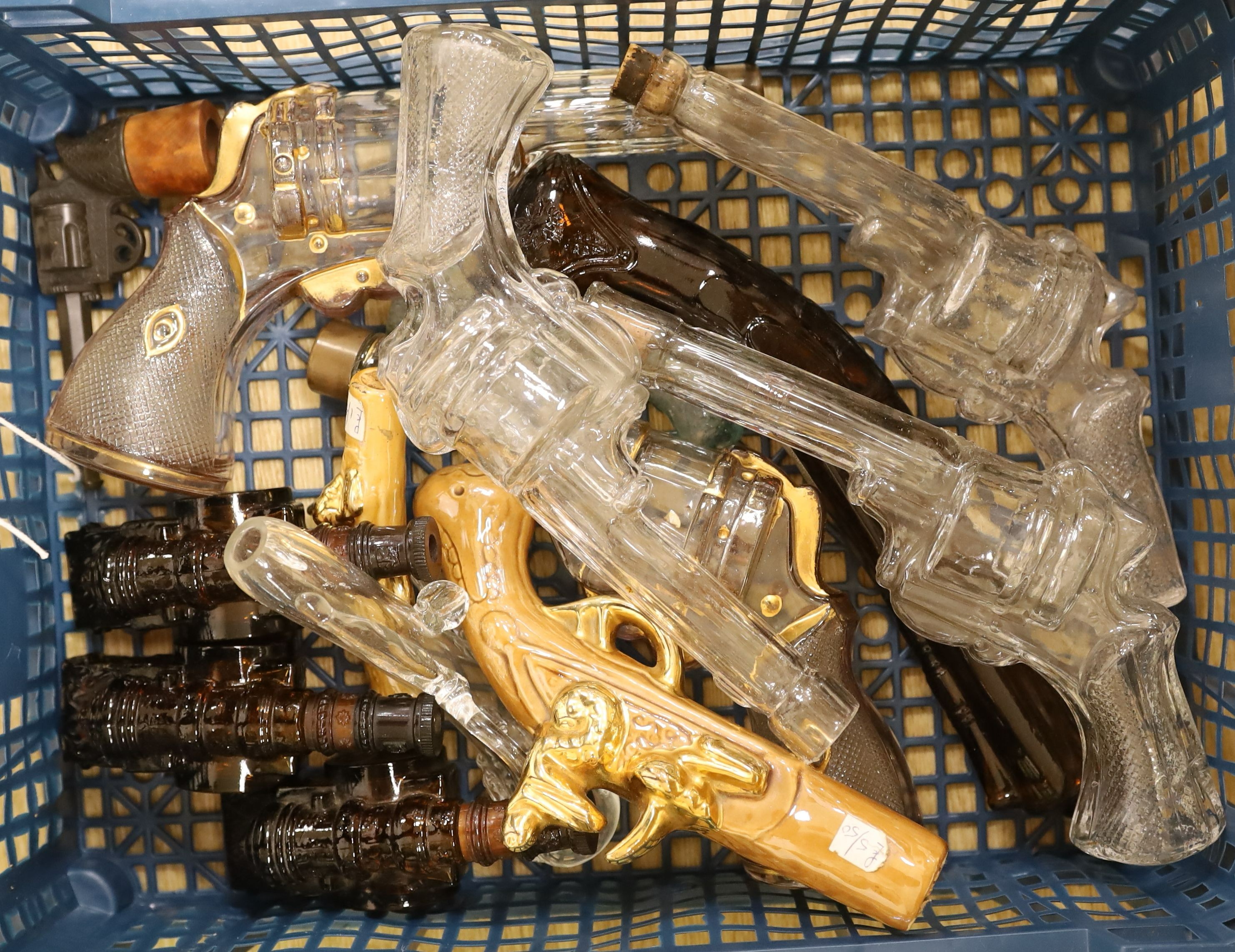 A novelty pressed bottle-green glass rifle and a collection of novelty glass pistols and cannon, Rifle 105 cms high.